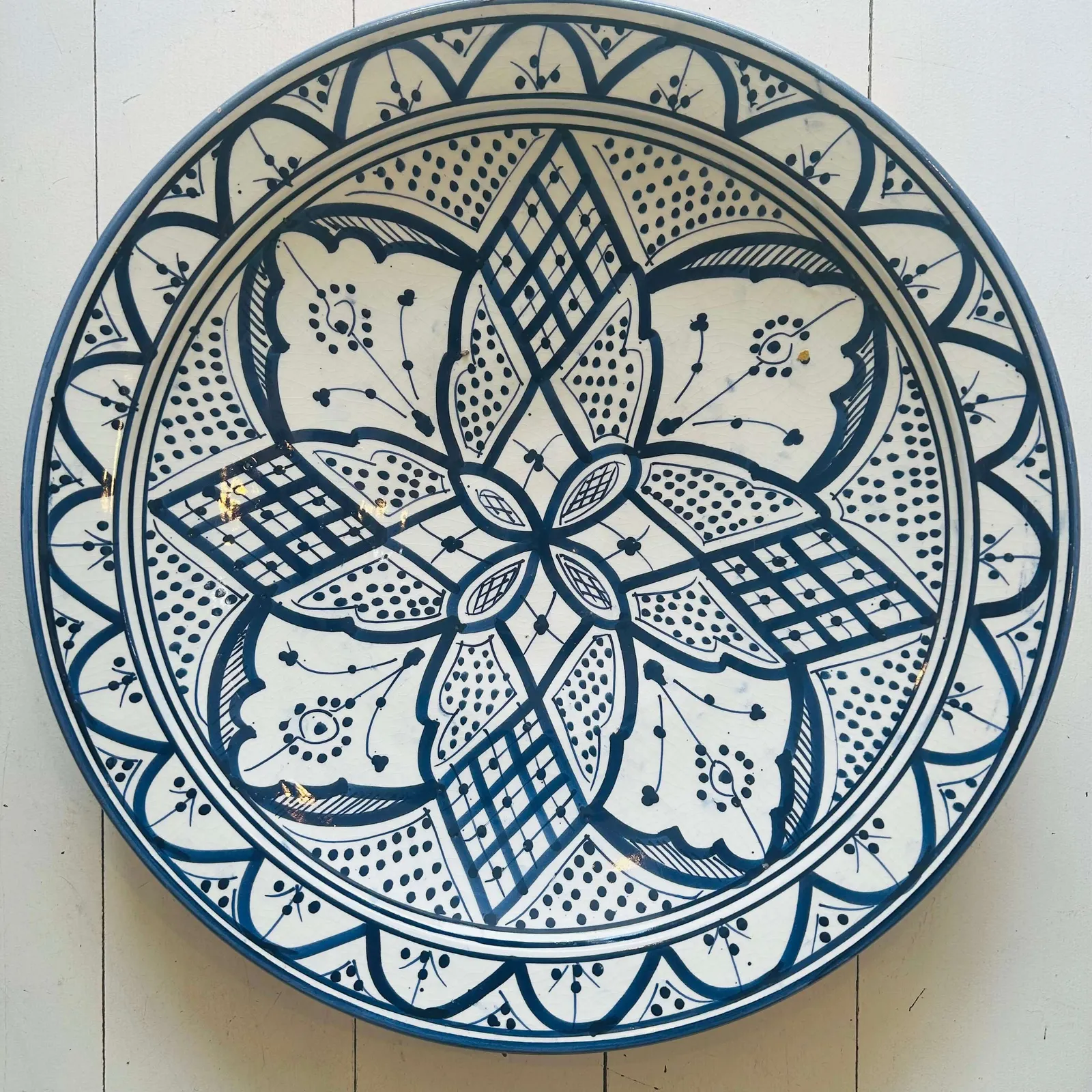 Assiette Safi artisanale en céramique rouge avec trou de suspension arrière.
